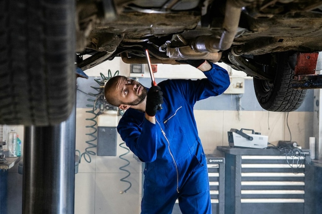 Mechanic performing inspection under commercial vehicle on lift
